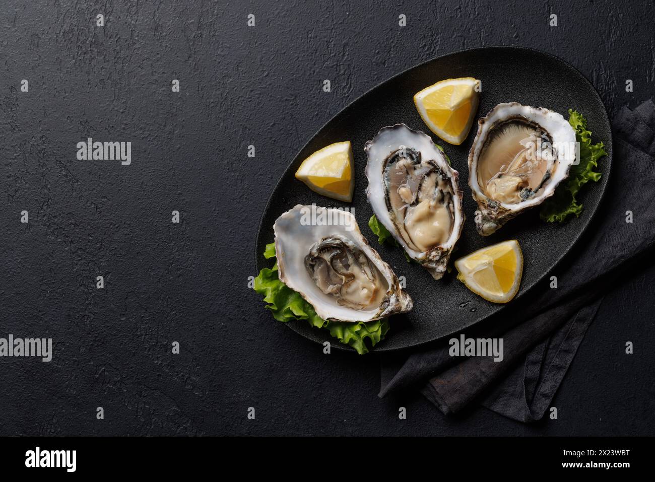 Frische Austern mit Zitrone auf Teller. Flache Ladefläche mit Kopierraum Stockfoto