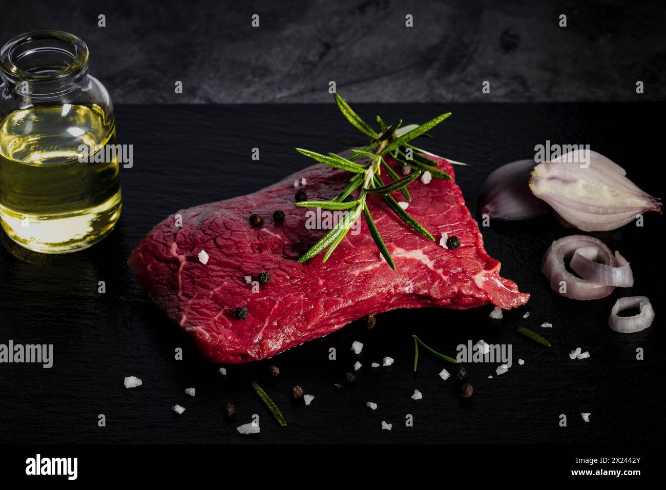 Rohes, leicht marmoriertes Rindersteak mit Pfeffer, Salz und Rosmarin Stockfoto