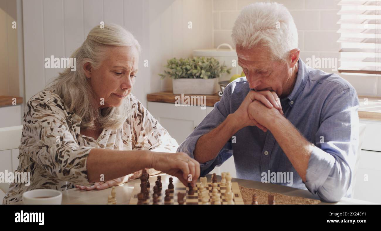Senior, Rentner und Paar zu Hause mit Schach im Brettspiel durch Bindung, Denken und Strategie für Entscheidungen. Ältere Menschen, Mann und Frau in der Küche Stockfoto