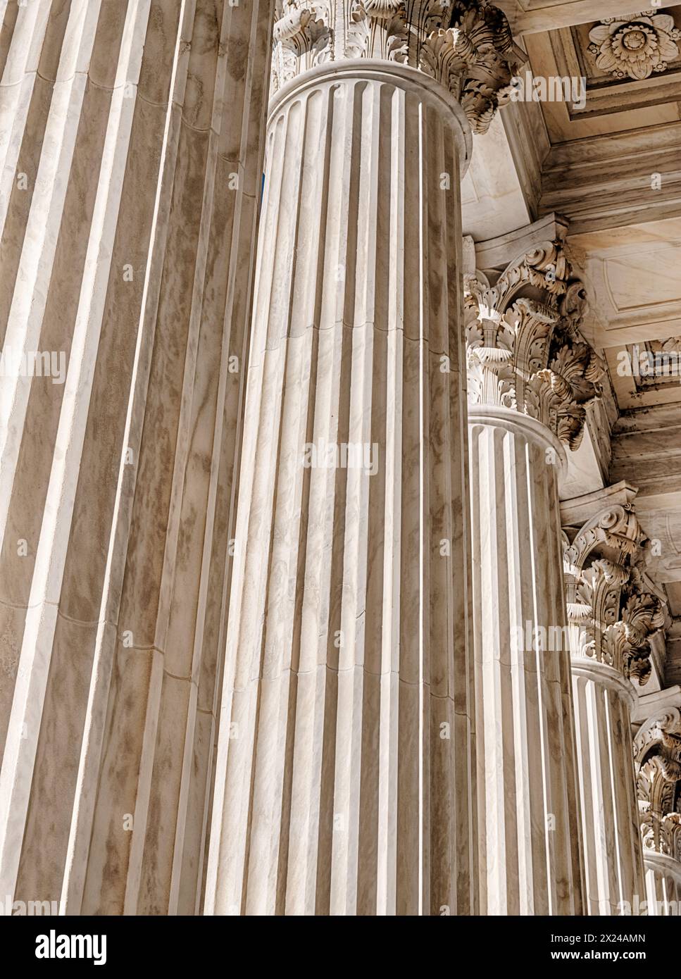 Die hohen Marmorsäulen vor dem Obersten Gerichtshof der Vereinigten Staaten werden von Sonnenlicht beleuchtet und vermitteln ein Gefühl der Gerechtigkeit. Stockfoto