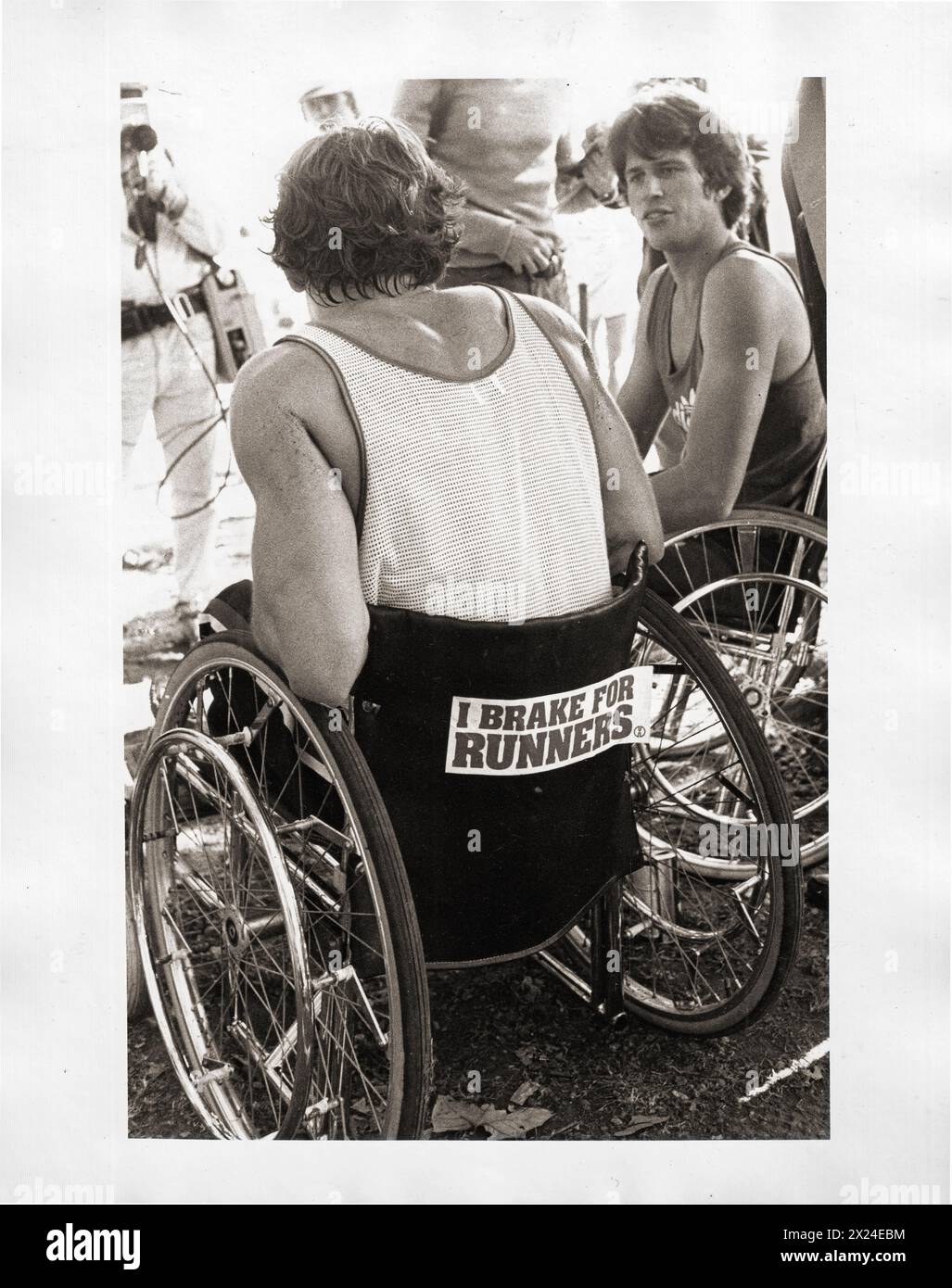 Rollstuhlläufer sprechen nach dem New Yorker Marathon. 1981 im Central Park, NYC. Auf dem Aufkleber steht „I Brake for Runners“ (I Bremse für Läufer). Stockfoto