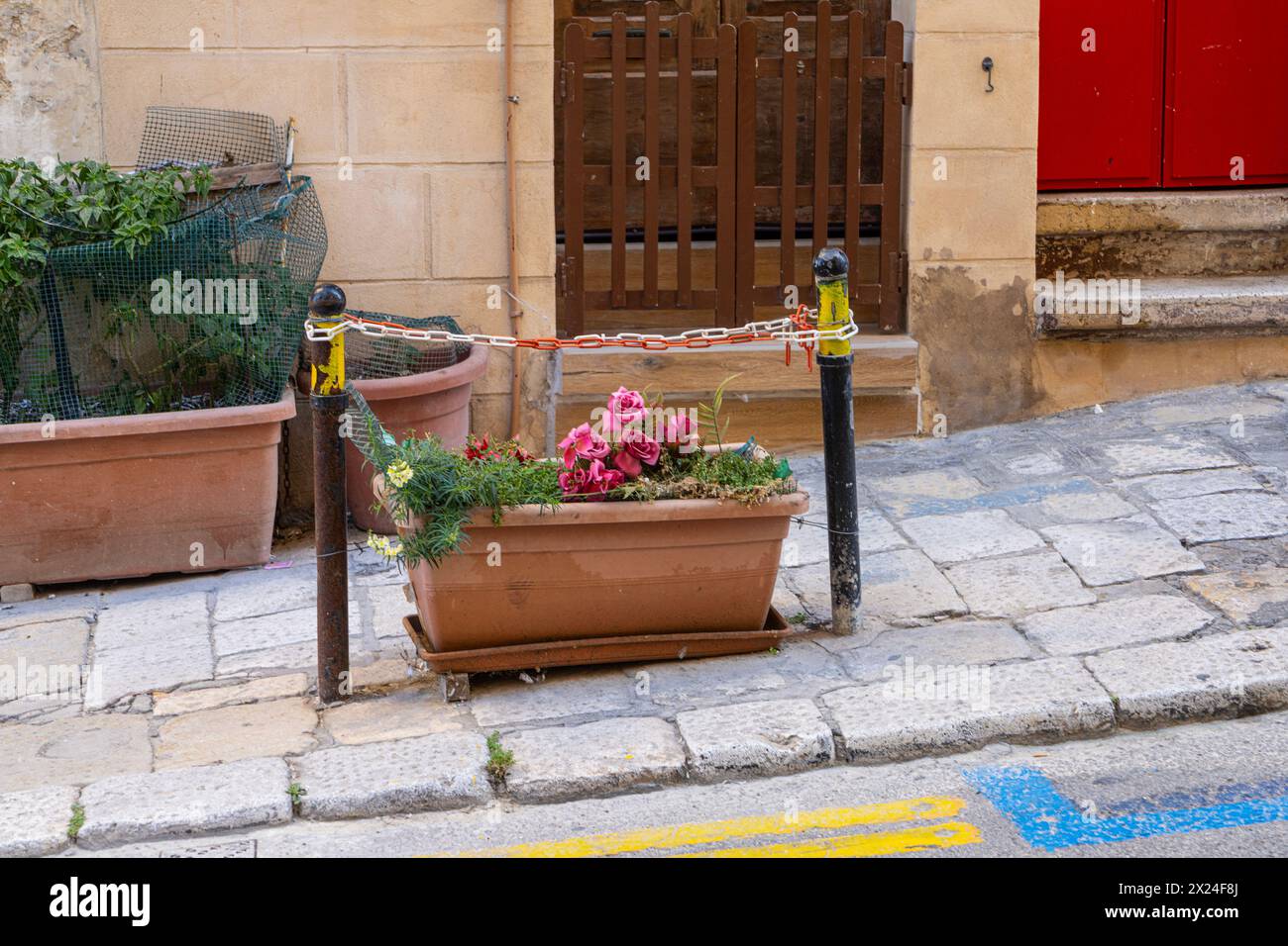 Eine Vase mit Blumen auf dem Bürgersteig des historischen Zentrums einer Stadt Stockfoto Eine Vase mit Blumen auf dem Bürgersteig des historischen Zentrums einer Stadt Stockfoto