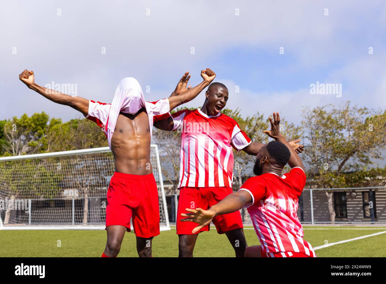 Drei afroamerikanische junge männliche Athleten feiern ein Tor auf einem Fußballfeld im Freien Stockfoto