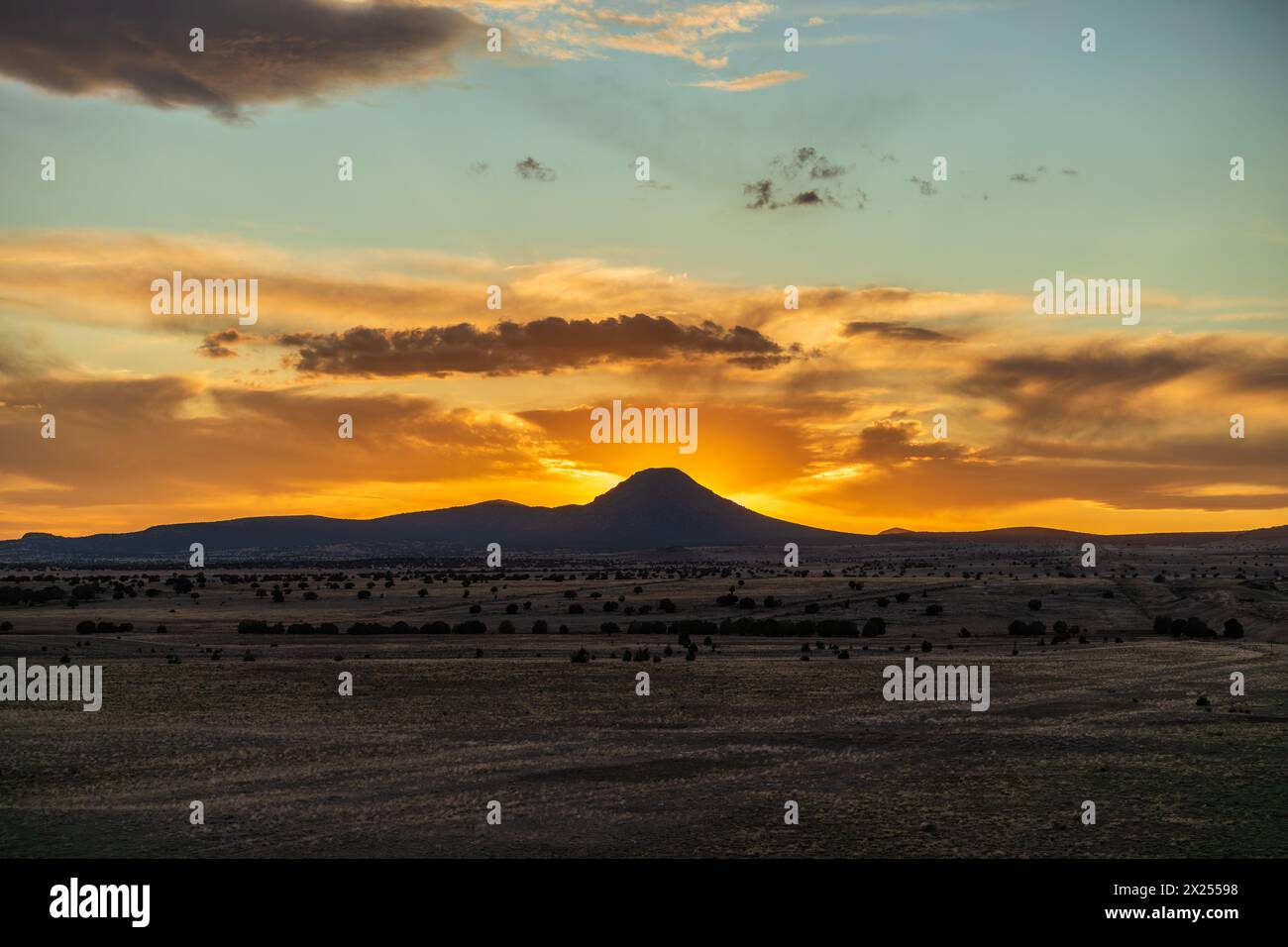 Entfernter Berg bei Sonnenuntergang mit dramatischen orangen Wolken Stockfoto