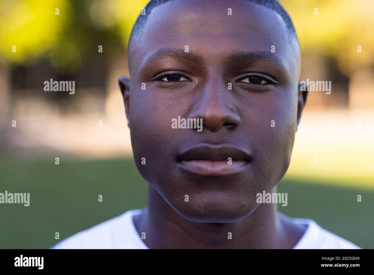 Afroamerikanischer junger männlicher Athlet, der auf einem Feld steht, direkt auf die Kamera blickt, den Kopierraum Stockfoto