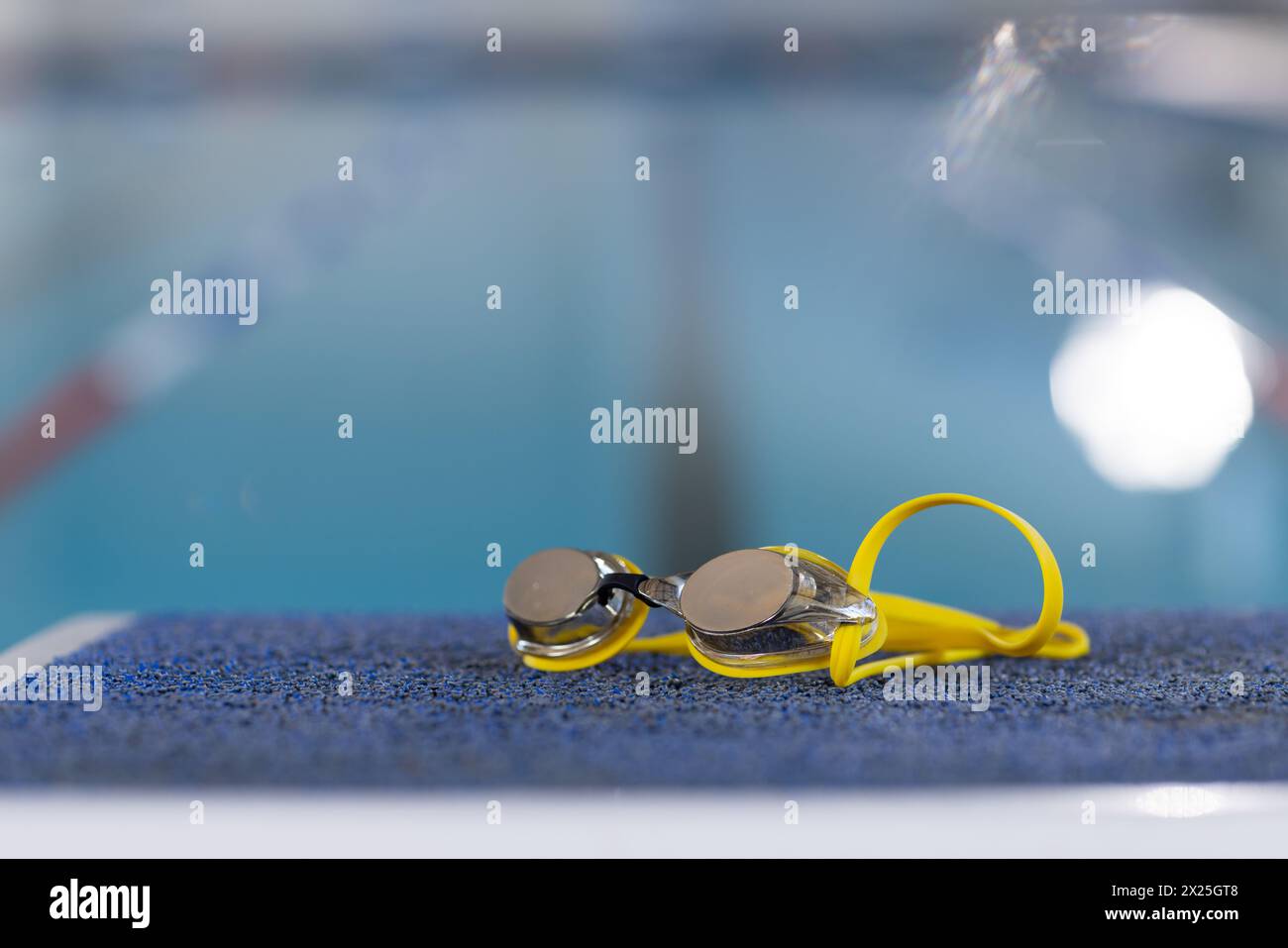 Schwimmbrille am Rand des Pools im Innenbereich, klares Wasser reflektierendes Licht, Kopierraum Stockfoto