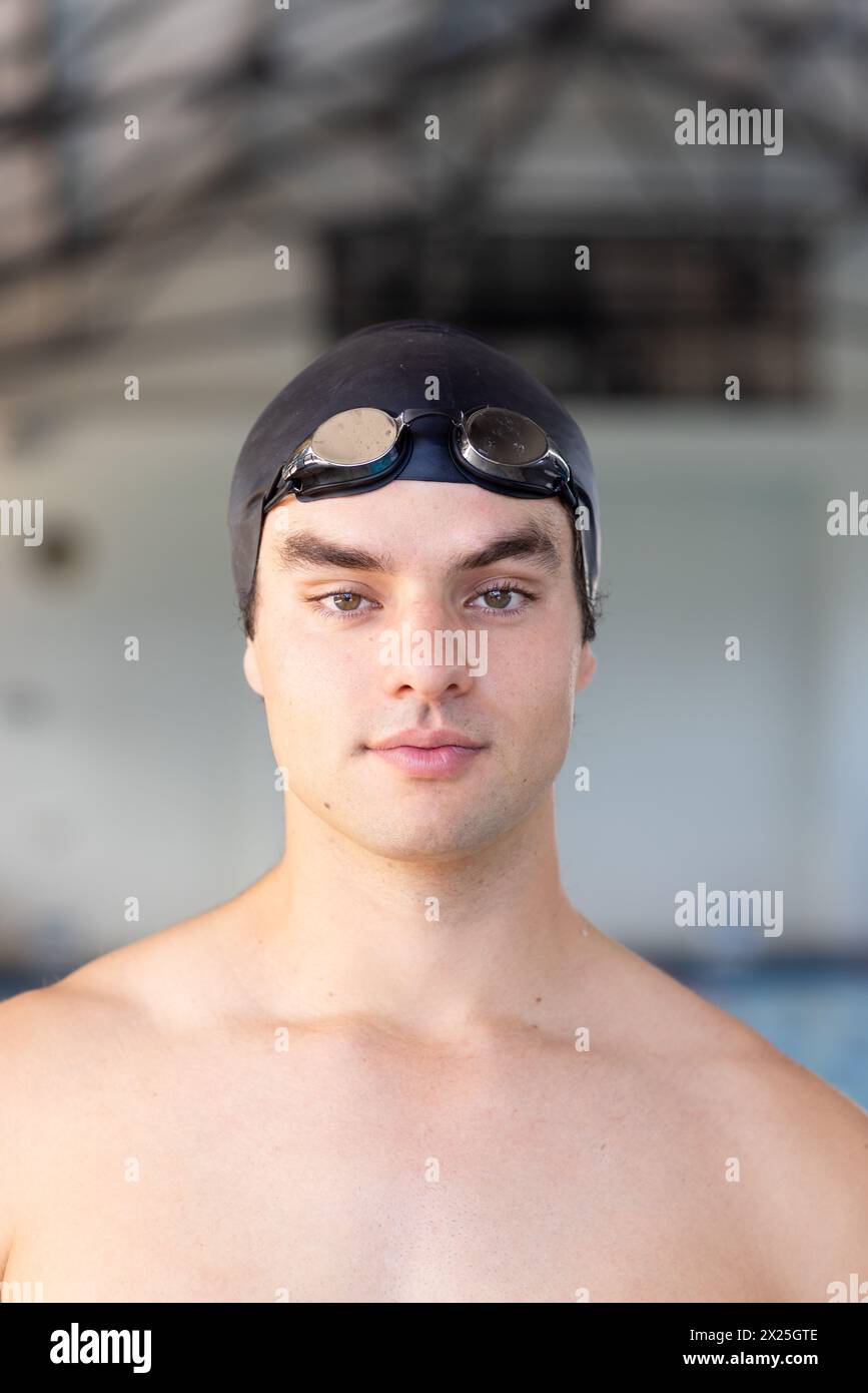 Kaukasischer junger männlicher Schwimmer, der drinnen steht und direkt in die Kamera blickt Stockfoto