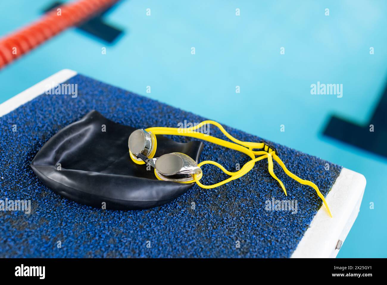 Schwimmbrille und Mütze liegen im Innenbereich auf dem Poolrand Stockfoto
