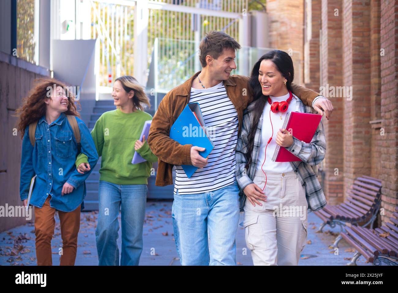 Multiethnische Gruppe fröhlicher und lächelnder Schüler mit Notizbüchern im Handlauf. Stockfoto