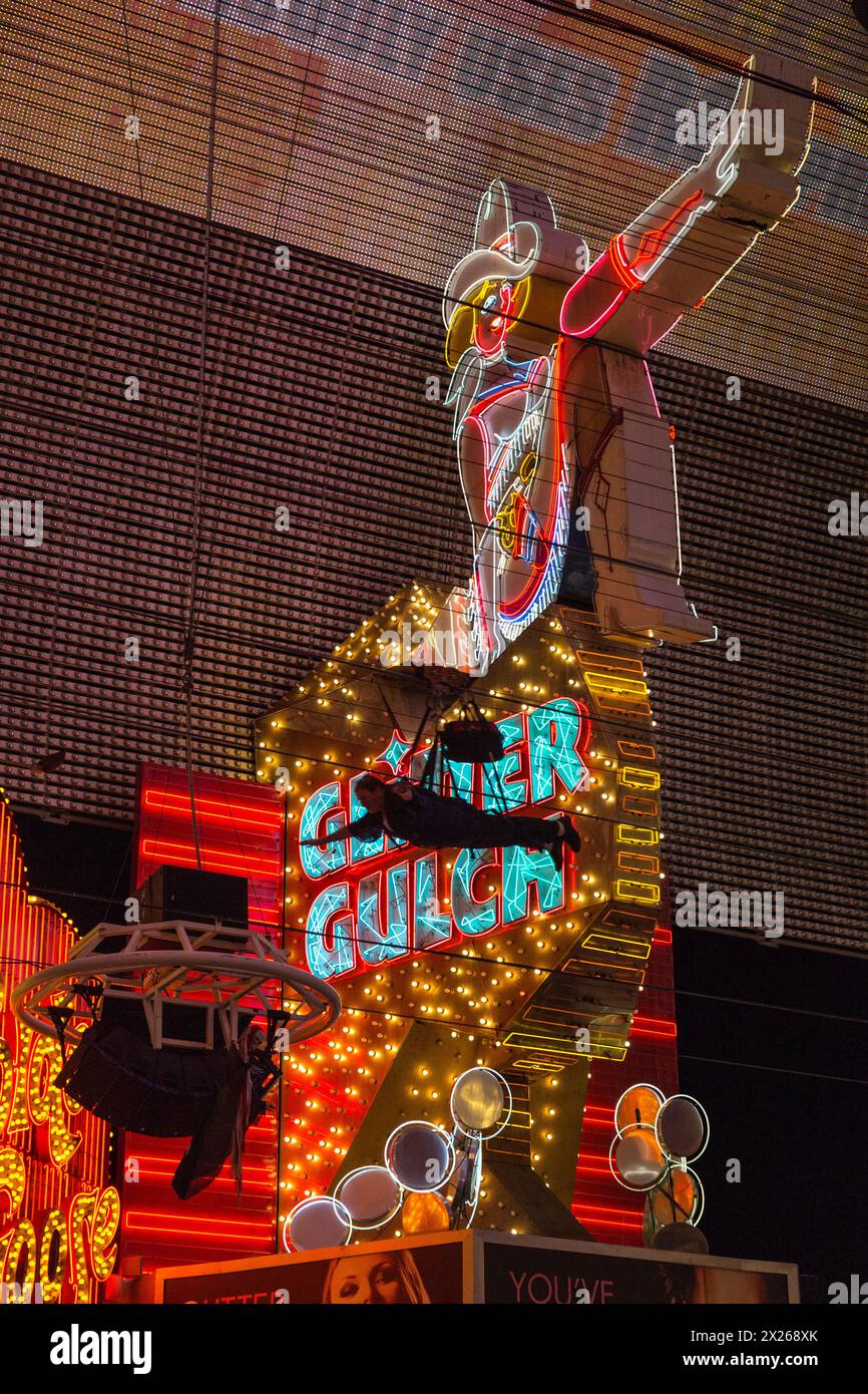 Las Vegas, Nevada.  Fremont Street.  Glitter Gulch Cowgirl Schild mit Zip Line Rider fliegen Vergangenheit. Stockfoto