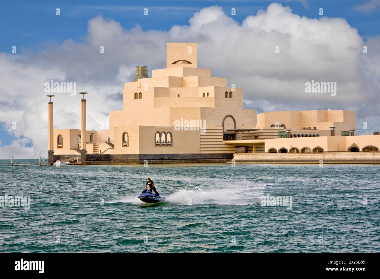 Doha, Katar. Museum für islamische Kunst, entworfen vom Architekten I.M. Pei. Ein Jet-Skier genießt die Gewässer des Persischen (Arabischen) Golfs. Blauer Himmel und Cumulu Stockfoto