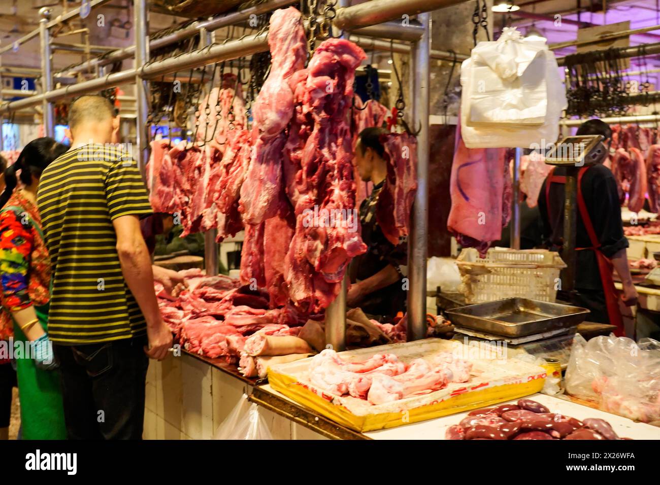 Chongqing, Provinz Chongqing, China, Blick auf einen geschäftigen Fleischmarkt mit Kunden und hängenden Fleischstücken, Chongqing, Provinz Chongqing, China Stockfoto