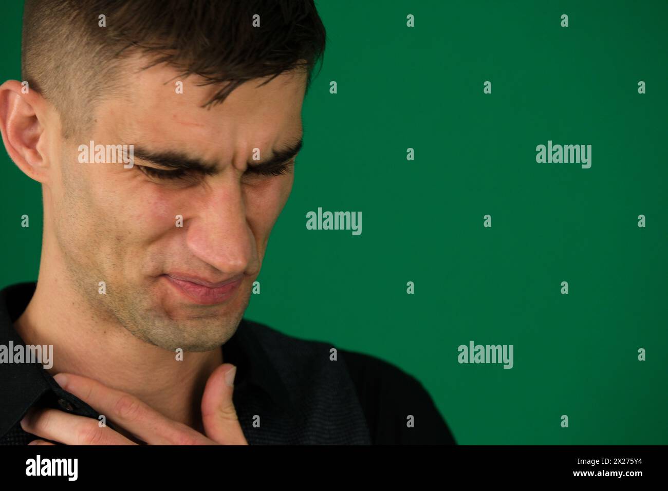 Nahaufnahme Porträt eines lustigen weinenden Mannes Emotionen eines gutaussehenden Mannes auf grünem Hintergrund Chromakey Nahaufnahme dunkles Haar junger Mann. Männer zeigen Brustschmerzen. Stockfoto