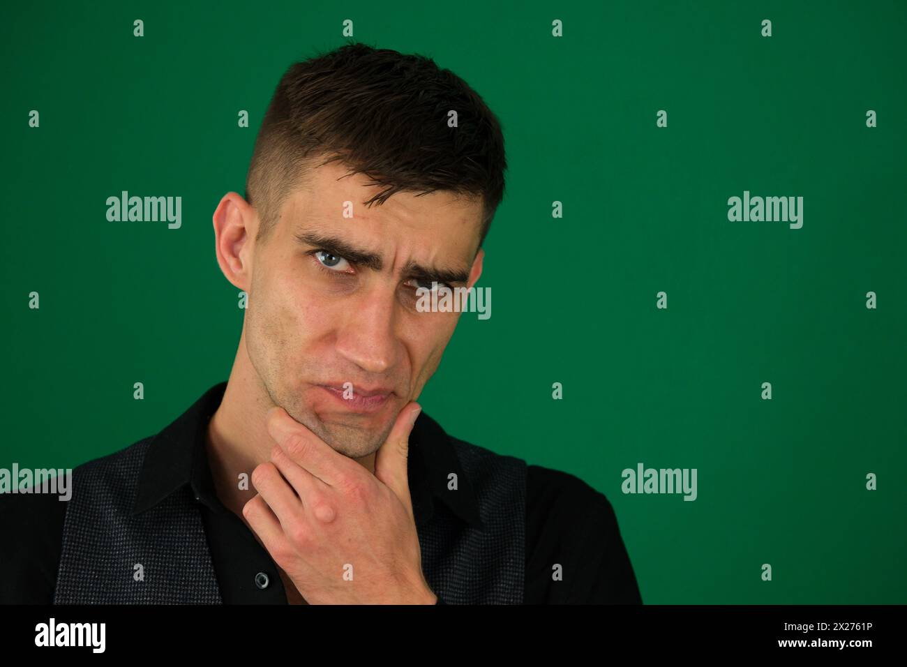 Emotionen eines gutaussehenden Mannes auf grünem Hintergrund, Chromakey-Nahaufnahme, dunkles Haar, junger Mann. Nahaufnahme eines gutaussehenden männlichen Teenagers Stockfoto