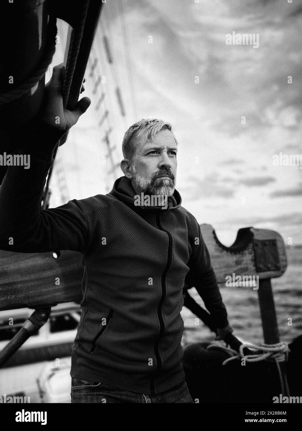 Halblanges Porträt eines kontemplativen mittelerwachsenen Mannes, der auf einem Segelboot steht Stockfoto