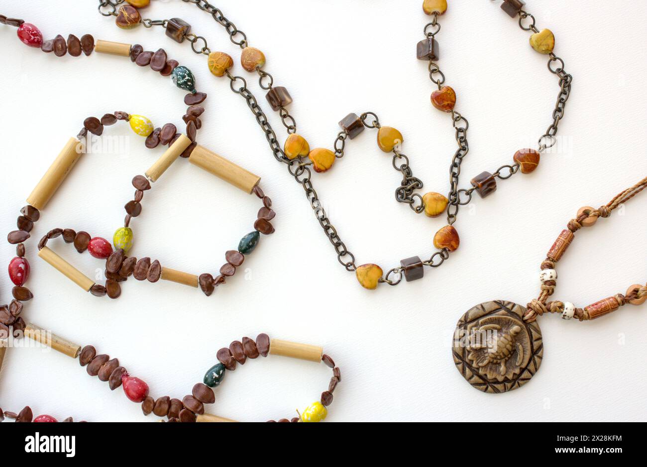 Set aus brasilianischen handgemachten Halsketten auf weißem Hintergrund. Damenmode mit geschnitztem Holzanhänger und braunen und gelben Perlen. Stockfoto