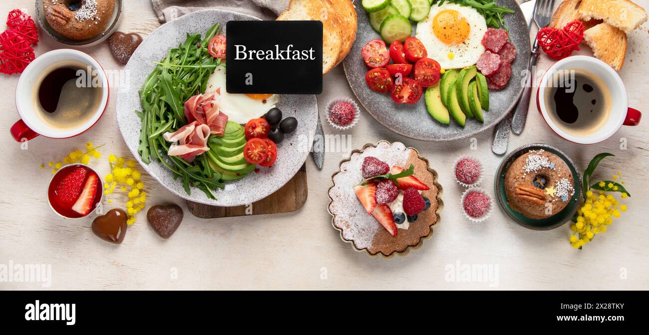 Frühstück mit Kaffee, frischer Bäckerei, Eiern, Salat, Fleisch und Obst. Urlaubskonzept. Draufsicht. Kopierbereich. Stockfoto