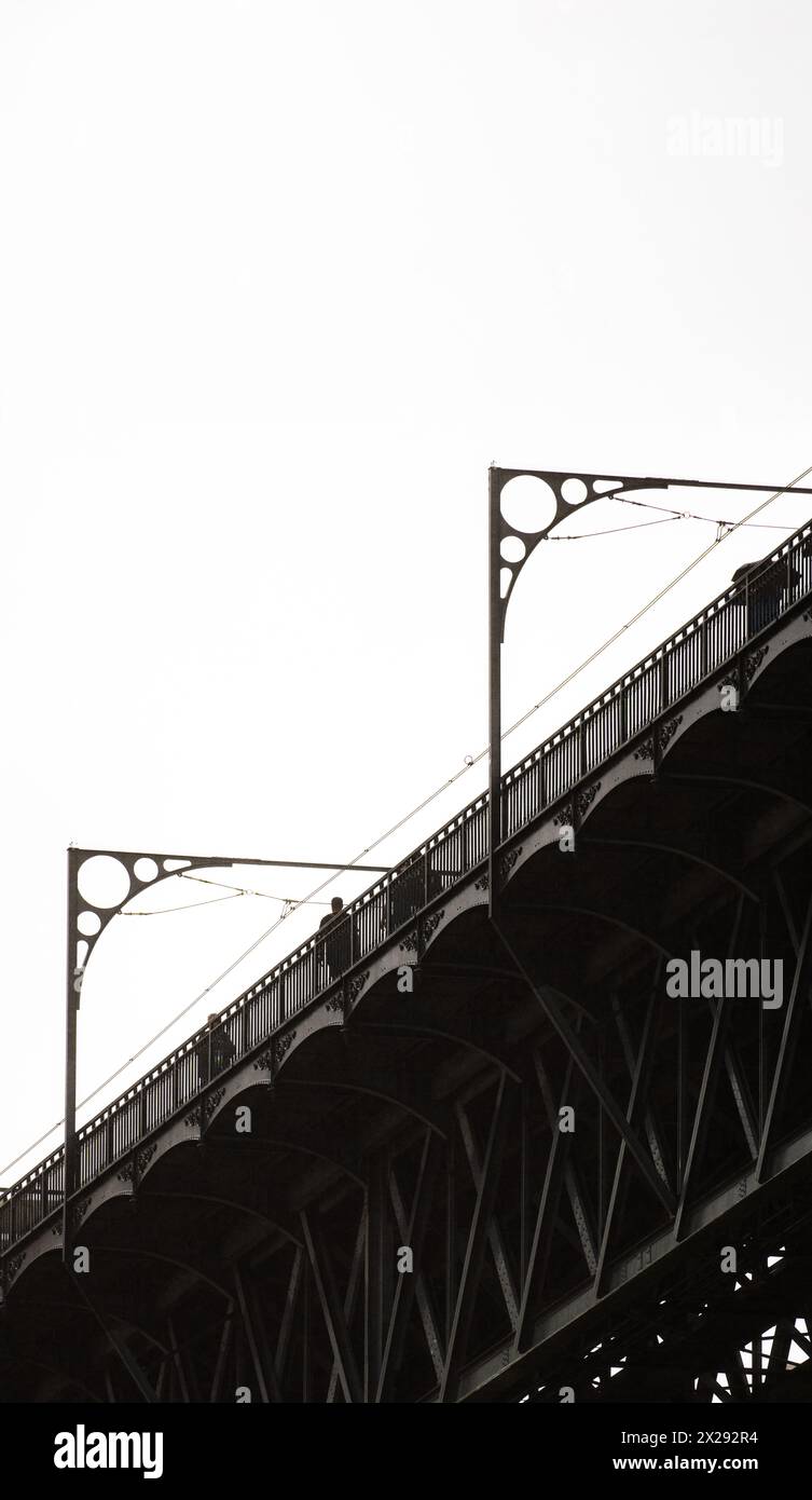 Silhouette von Menschen, die auf der oberen Plattform der Don Luis I Stahlbrücke in Porto laufen, mit Details der Metallkonstruktion und der durchgehenden Kabel Stockfoto