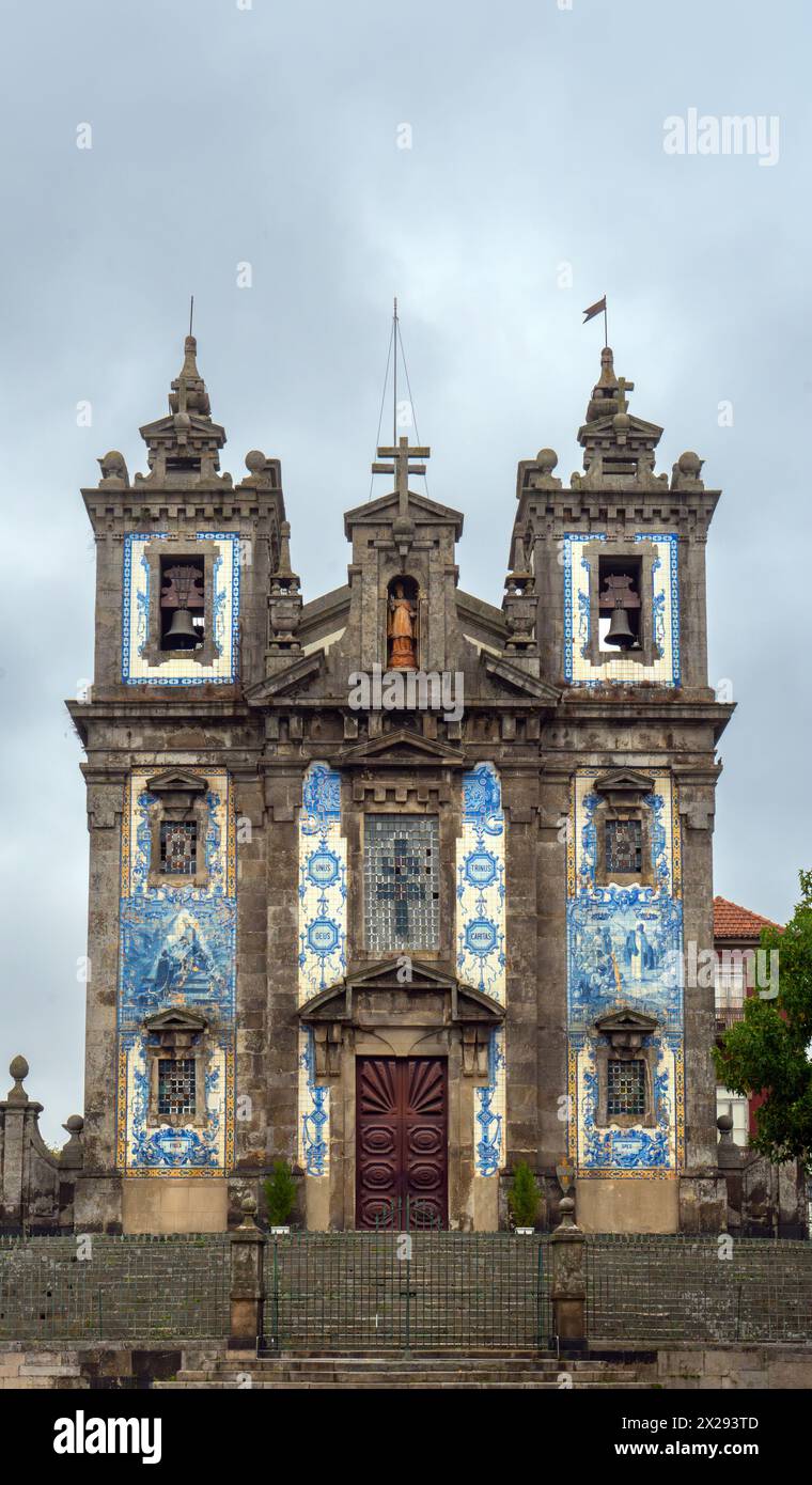 Kirche von San Ildefonso mit einer Fassade, die mit blau-weißen Keramikfliesen bedeckt ist und bei Sonnenaufgang religiöse Motive aufweist, unter grauem und bewölktem Himmel. Porto. Por Stockfoto
