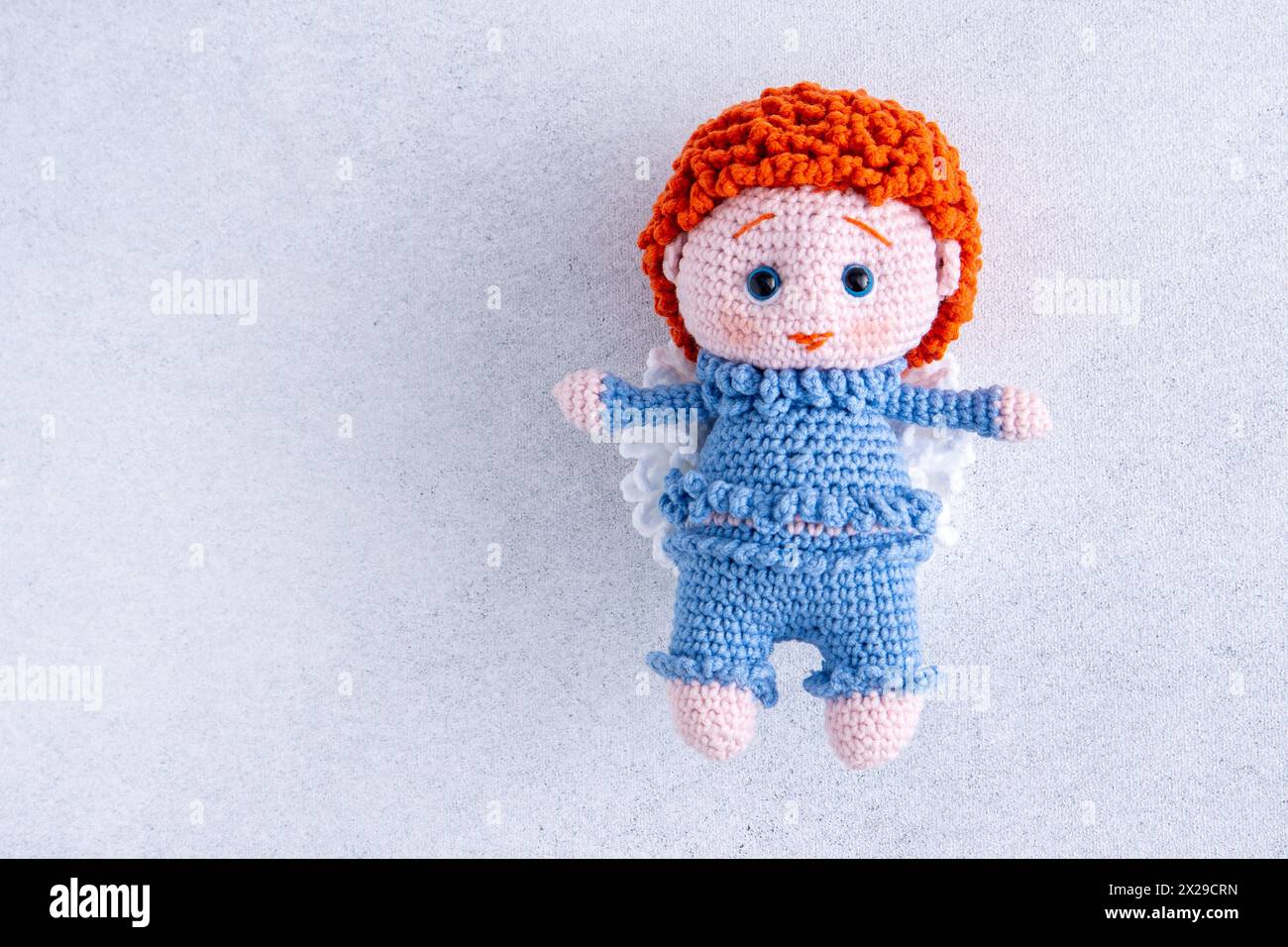 Gestricktes Kinderspielzeug. Junge Engel in einem blauen Anzug. Häkeln Stockfoto