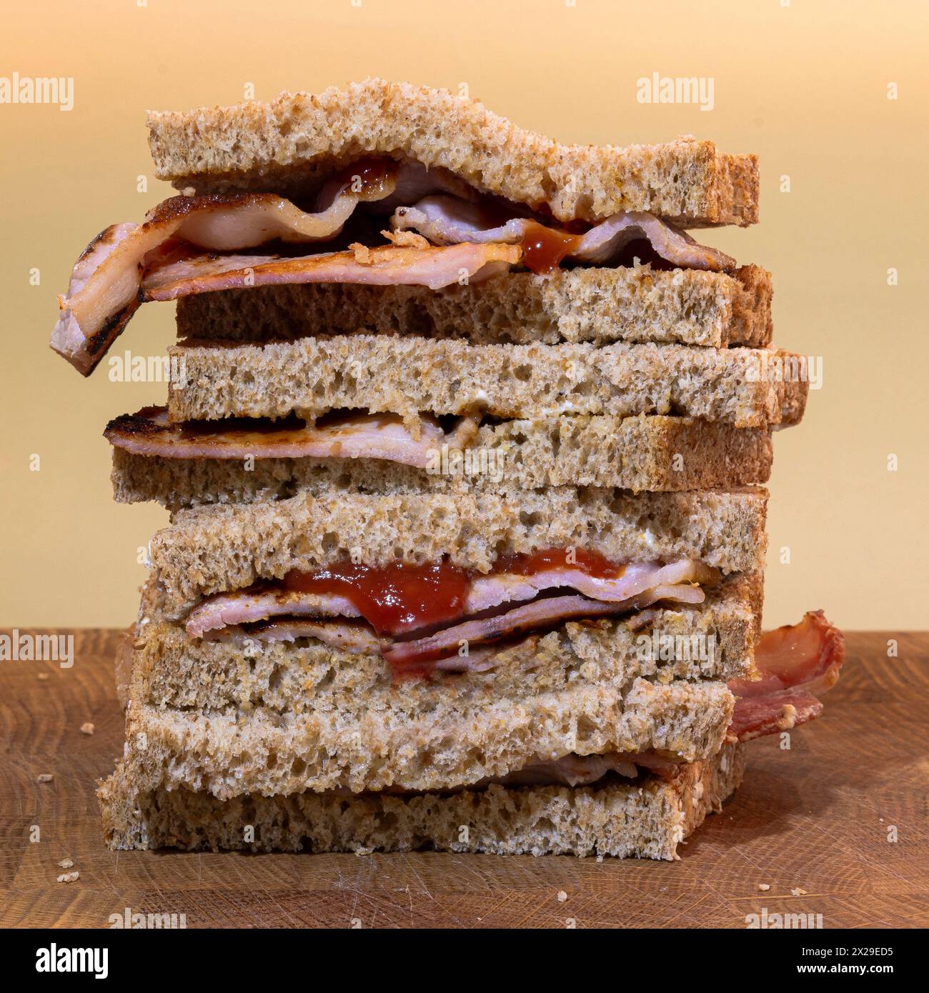 Ein Stapel Bacon-Sandwiches mit braunem Vollkornbrot und Tomatenketchup Stockfoto