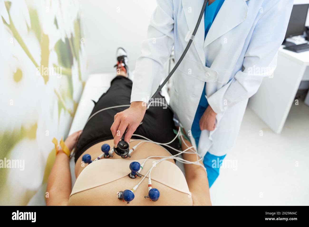 Ein Patient entspannt sich, während ein Arzt sorgfältig einen EKG-Test durchführt. Stockfoto