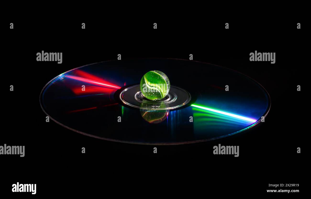 Eine grüne Glaskugel in der Mitte einer CD mit hellen Reflexionen auf dunklem Hintergrund. Stockfoto