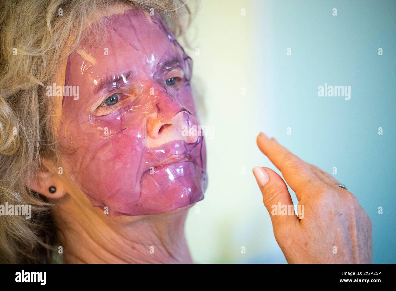 Reife Frau mittleren Alters mit einer lila Gel Gesichtsmaske für Haut- und Schönheitspflege Stockfoto