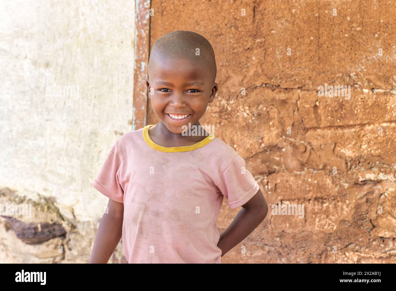 Glückliches afrikanisches Dorfkind, das vor dem Haus steht Stockfoto