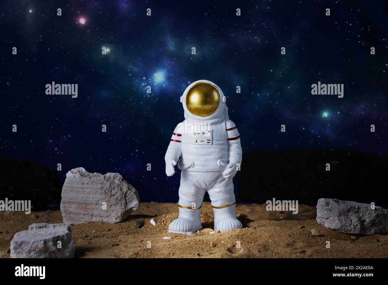Astronautenfigur über blauem Sternenhimmel, Kopierraum. Spielzeug des Raumfahrers. Raumfahrt- und Raumflugkonzept. Der Tag der Kosmonauten. Stockfoto