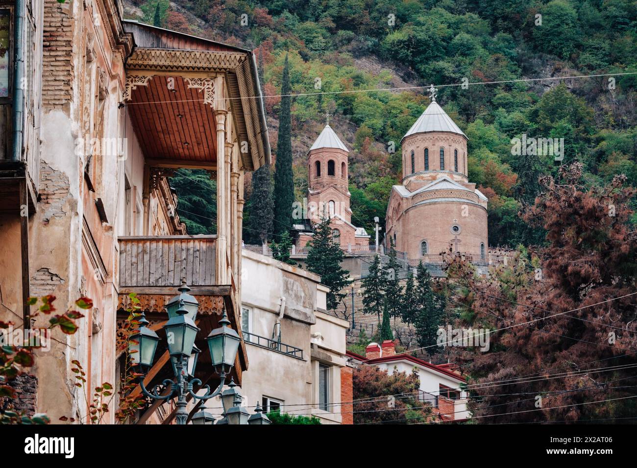 Blick auf die Mama Daviti-Kirche (auch Mtatsminda pantheon genannt) und einen traditionellen geschnitzten Holzbalkon in Tiflis (Georgien) Stockfoto