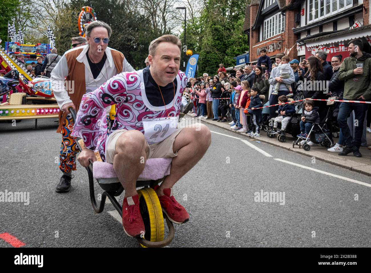 London, Großbritannien. 21. April 2024. Die Teilnehmer nehmen am „YE Olde Wheelbarrow Race“ in Pinner im Nordwesten Londons Teil. Die Veranstaltung sammelt Spenden für wohltätige Zwecke und ist Teil der Feierlichkeiten zum St. George’s Day. Quelle: Stephen Chung / Alamy Live News Stockfoto