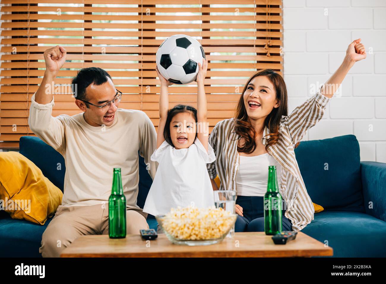 Eine glückliche Familie genießt den Nervenkitzel eines Fußballspiels zu Hause Stockfoto