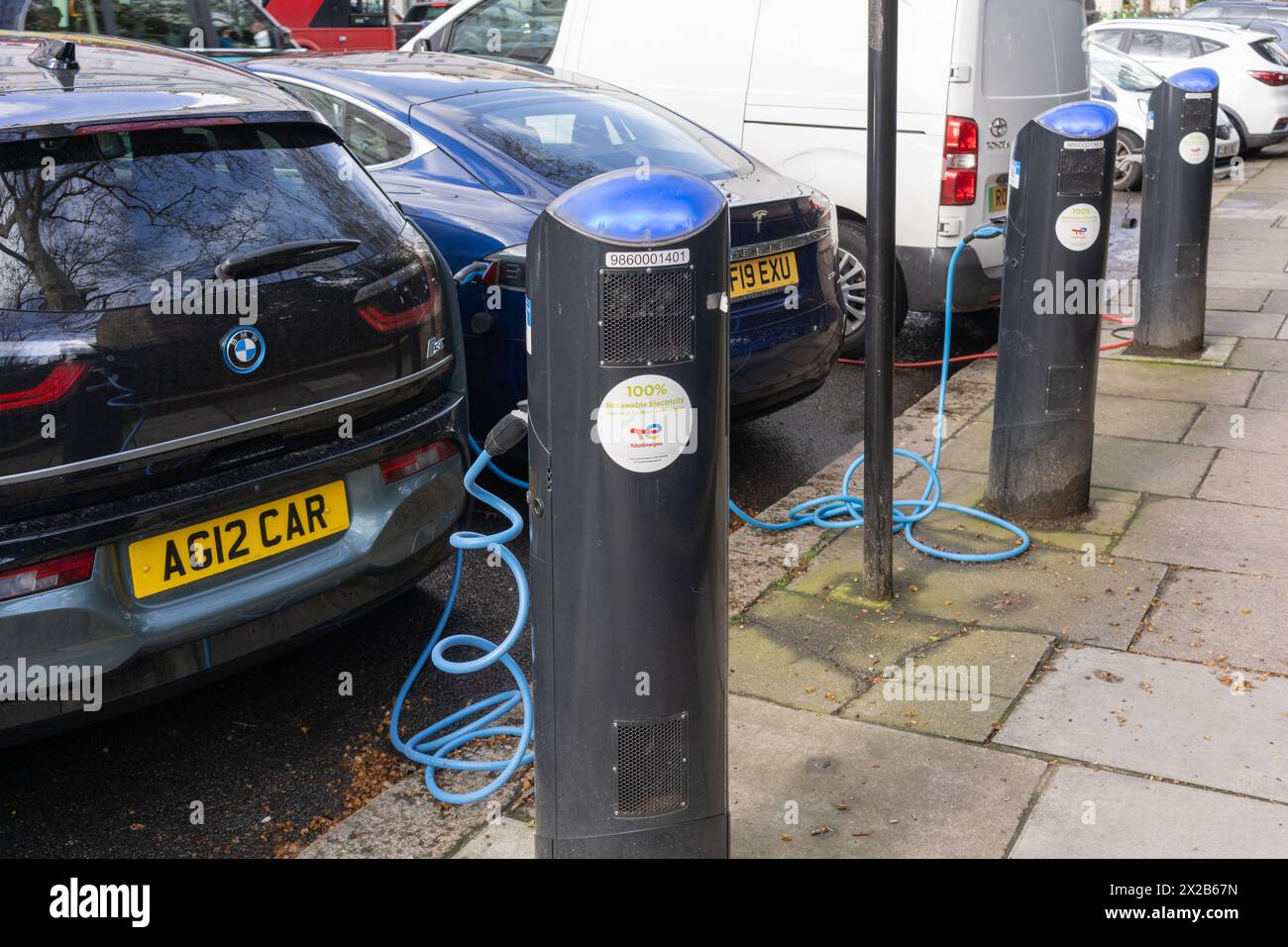 Elektroautos – ein BMW i3 und ein Tesla angeschlossen und geladen – an einer EV-Ladestation des öffentlichen Netzwerks von Source London. London, England Stockfoto