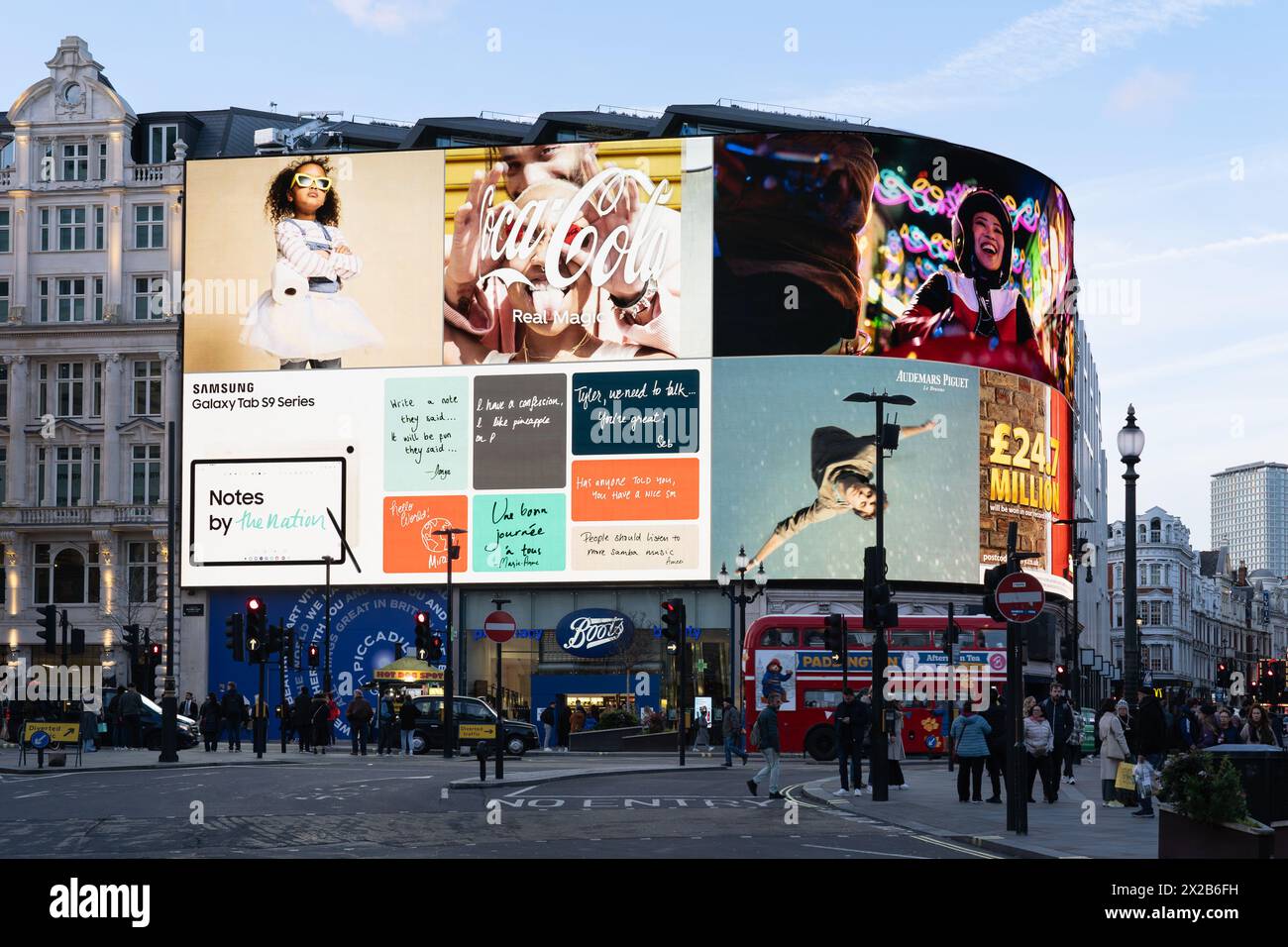 Riesige Neonschilder und Videodisplays an der Seite eines Gebäudes im Piccadilly Circus in London mit Fußgängern und einem Londoner Bus davor. England, Großbritannien Stockfoto