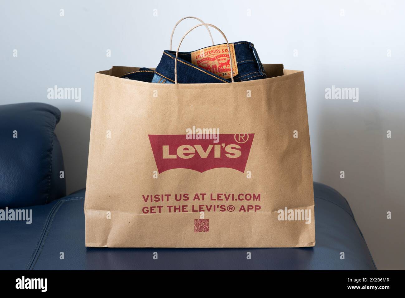 Eine Papiertüte mit Levi Strauss & Co Jeans, die in einem britischen Levi's Store gekauft wurde. Konzept: Mitgebrachte Kleidung, nachhaltige Einkaufstasche, Levi's Logo Stockfoto