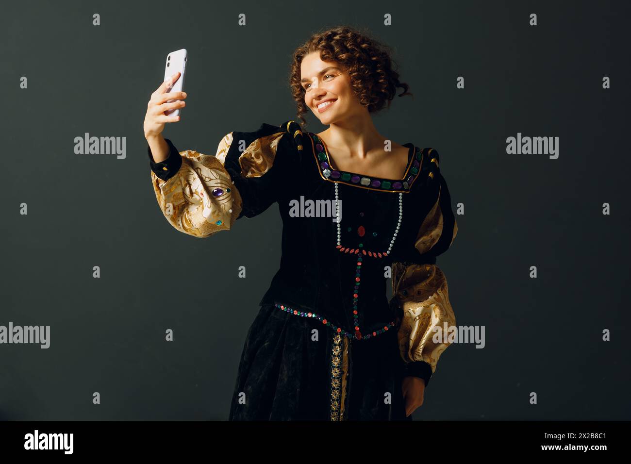 Porträt einer jungen Aristokratin, die ein Foto-Selfie mit Handy macht und in einem mittelalterlichen Kleid gekleidet ist Stockfoto