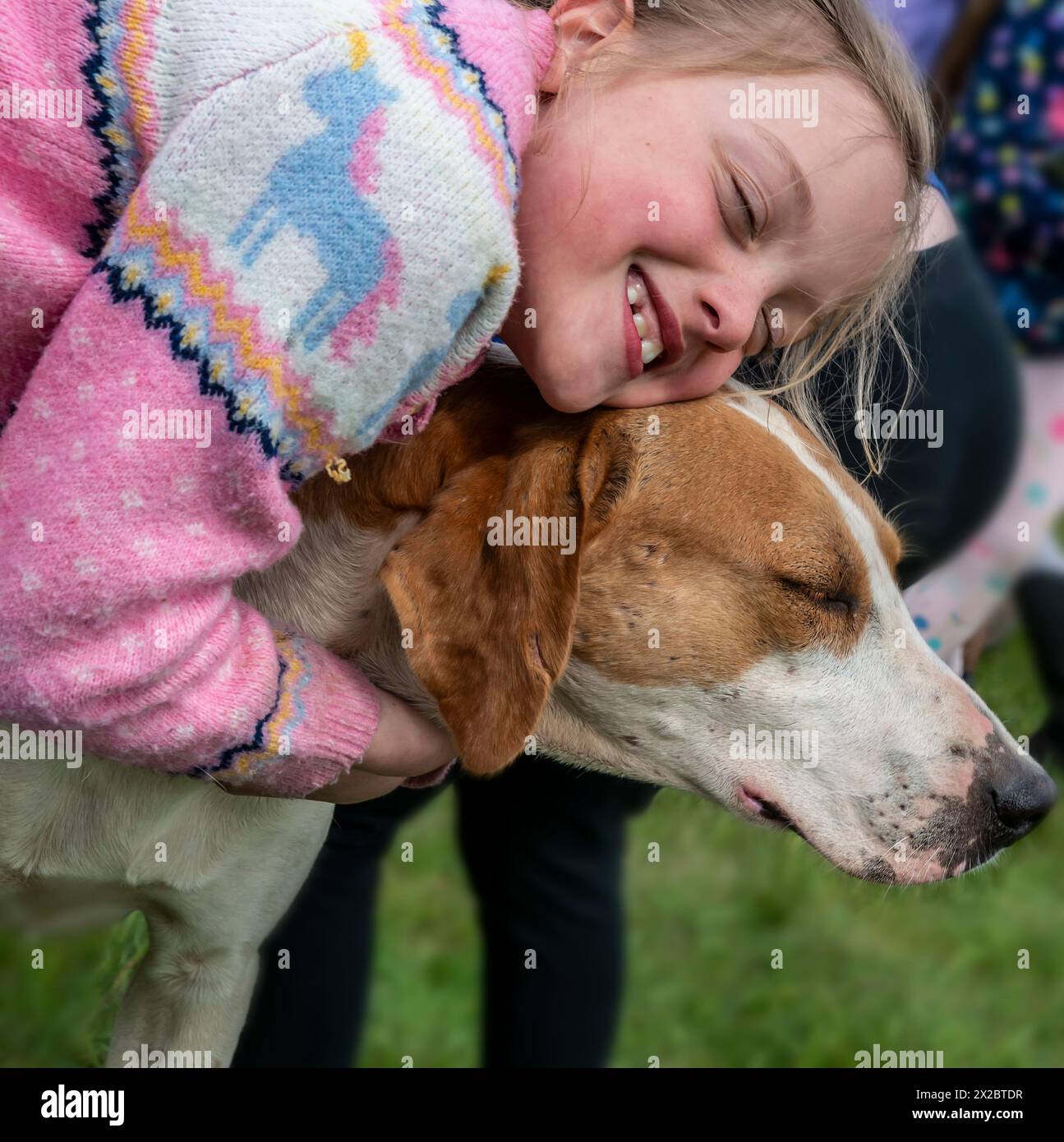 Kinder kuscheln einer der Hunde, die in die Rathbones Countryside Arena gebracht werden, um die Kinder bei Parham Races & Family Fun Day 2024 zu begrüßen Stockfoto