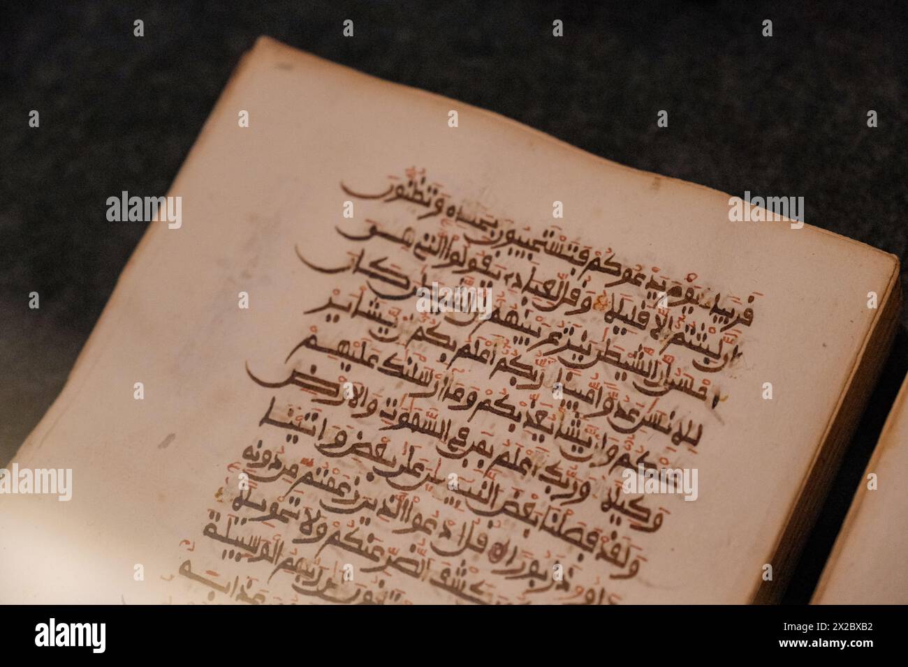 Eine Nahaufnahme, die die Schönheit alter arabischer Schriften auf einer historischen Koranseite enthüllt, ein Zeugnis für zeitlose Weisheit. Stockfoto