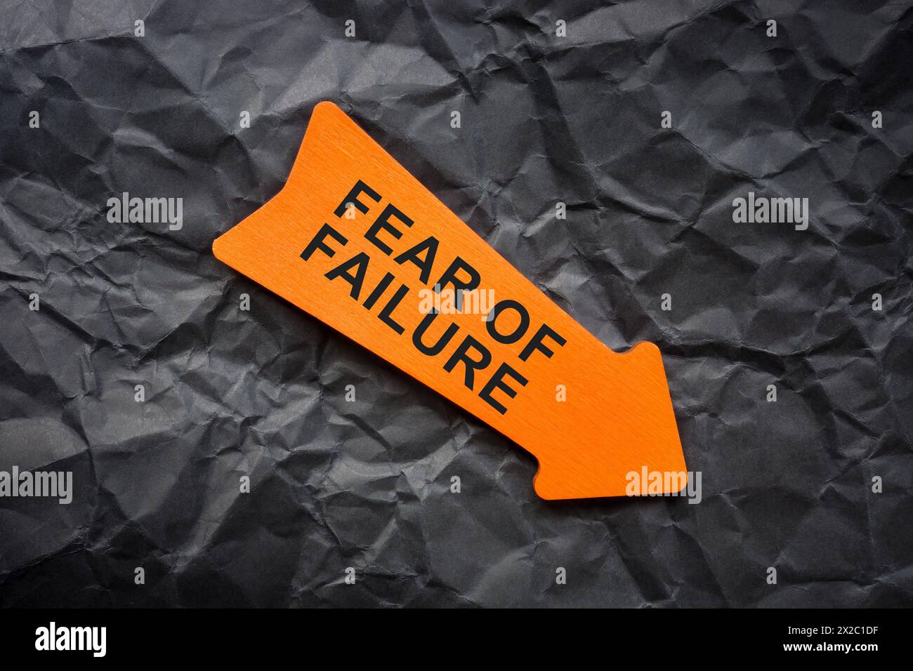 Kurzfassung über die Angst vor dem Versagen. Zerknittertes Papier und orangefarbener Pfeil. Stockfoto
