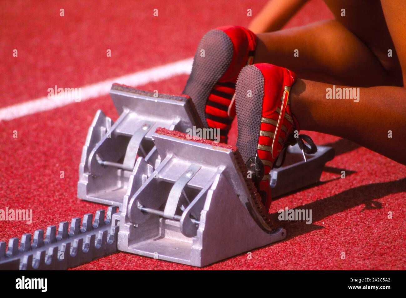 Nahaufnahme der Füße eines Sprinters bei Startblöcken auf einer Leichtathletikbahn Stockfoto