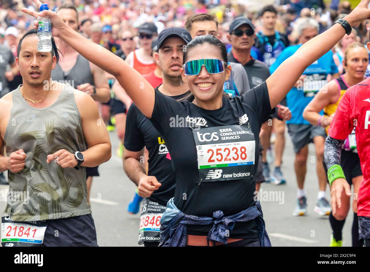 Die Läuferin hebt ihre Arme, um auf der Route des London Marathon 2024 fotografiert zu werden Stockfoto