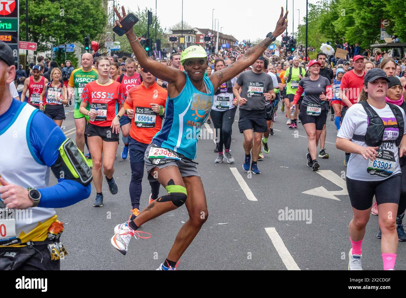 London Marathon 2024: Weibliche Läuferin tanzt mit breiten Armen auf der Route des 44. London Marathon Stockfoto