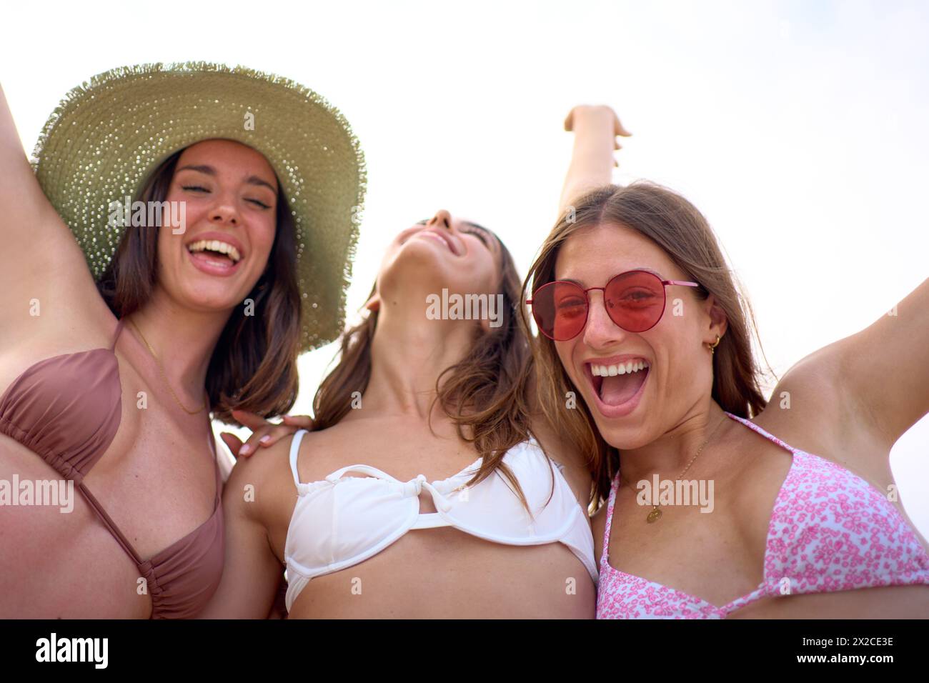 Niedriger Winkel. Porträt von aufgeregten Frauen der Gruppengeneration Z, die auf die Kamera schauen, die am Strand posiert Stockfoto