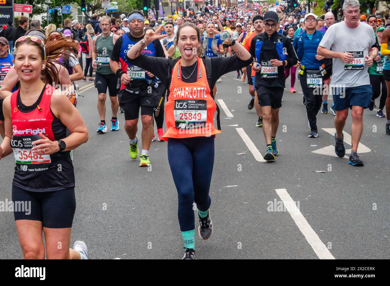 Die Läuferin hebt ihre Arme und streckt ihre Zunge heraus, während sie beim London Marathon 2024 posiert Stockfoto