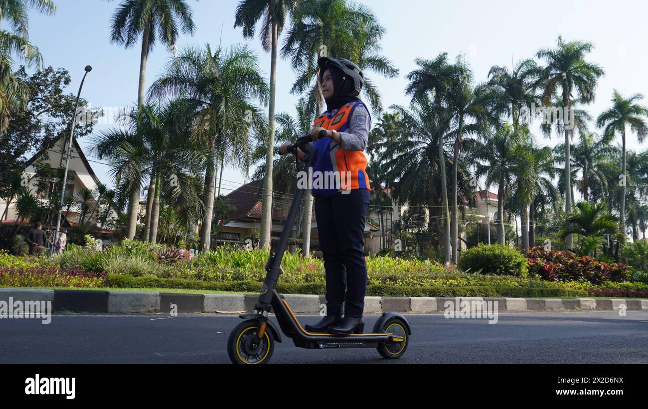 Ein Transportdienstmitarbeiter in Malang, der mit einem Elektroroller durch das autofreie Tagesgebiet reiste Stockfoto