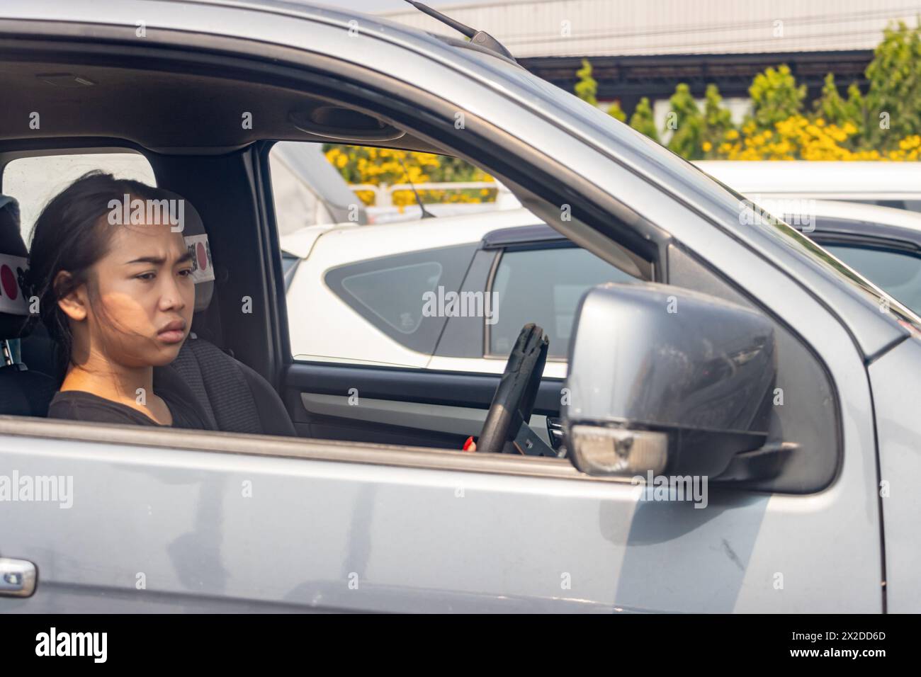 BANGKOK, THAILAND, 13. April 2024, Eine junge Frau, die in einem Konvoi auf der Autobahn fährt, beobachtet den Verkehr im Rückspiegel Stockfoto