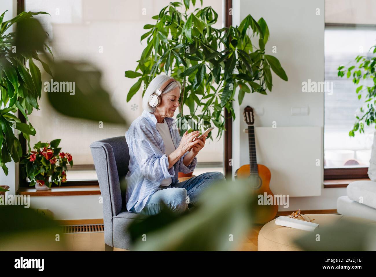Ältere Frau mit Kopfhörern, Musik hören, zu Hause entspannen. Stockfoto