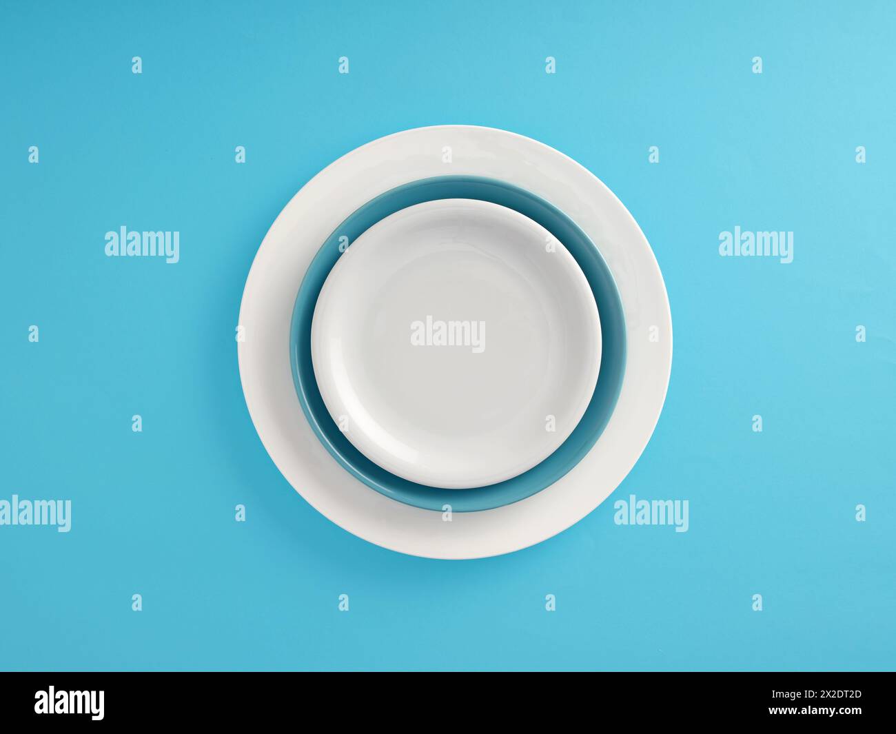 Hintergrund zu Lebensmitteln. Leere weiße Keramikplatte auf blauen und weißen Platten auf blauem Hintergrund. Stockfoto