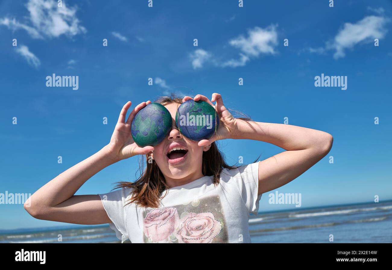 Kinder spielen am Strand von Westward Ho!, Devon mit ihren erdgemalten Kieseln zum Welttag der Erde am 22. April 202 Stockfoto